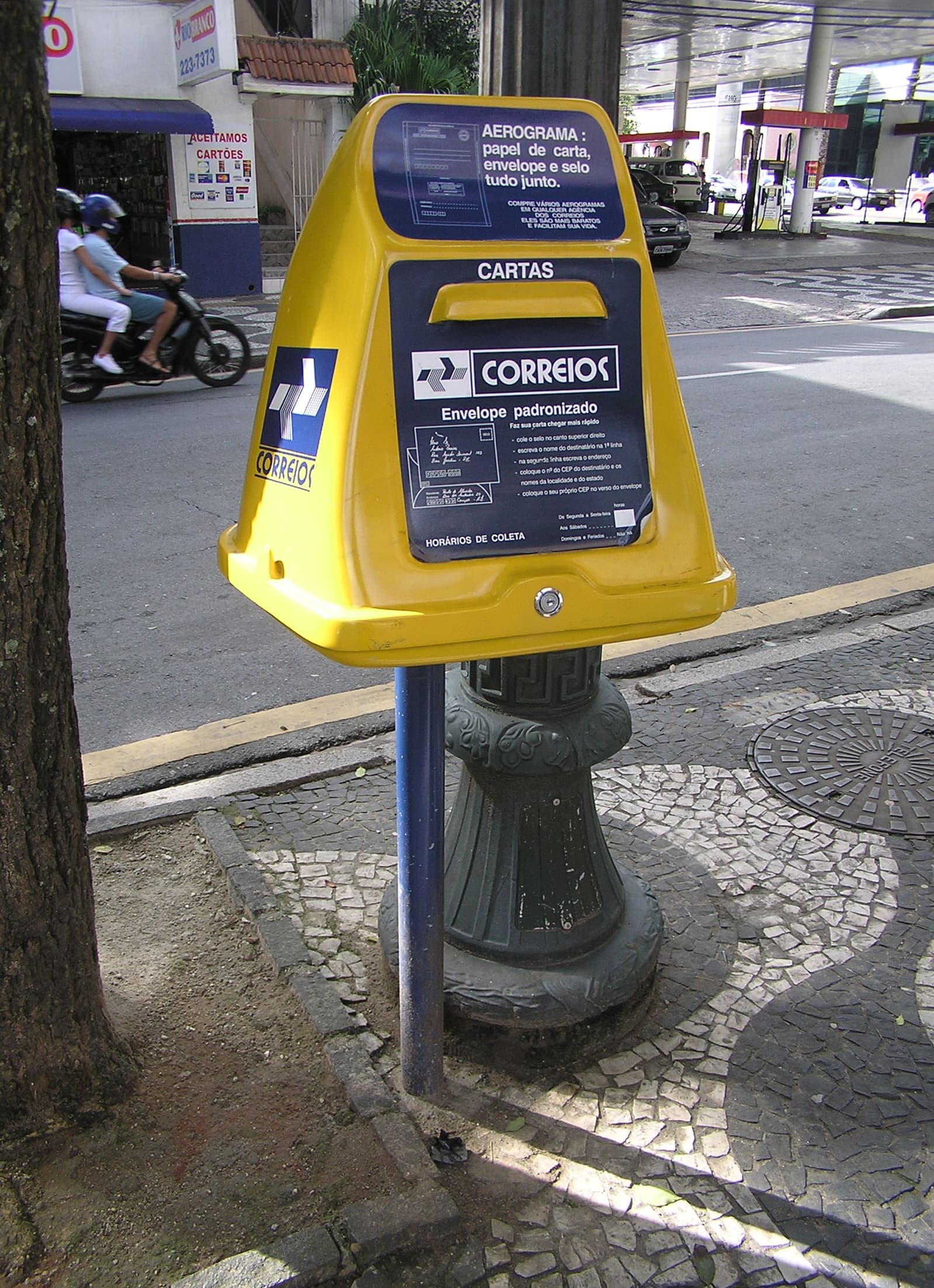 Caixa de coleta amarela dos Correios numa calçada de Belo Horizonte